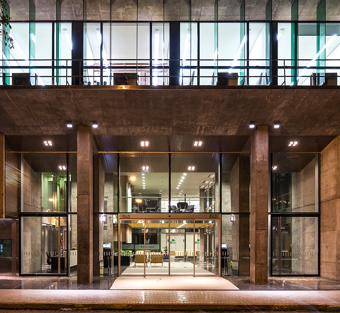 Entrada moderna de edificio con fachada de vidrio e iluminacion calida